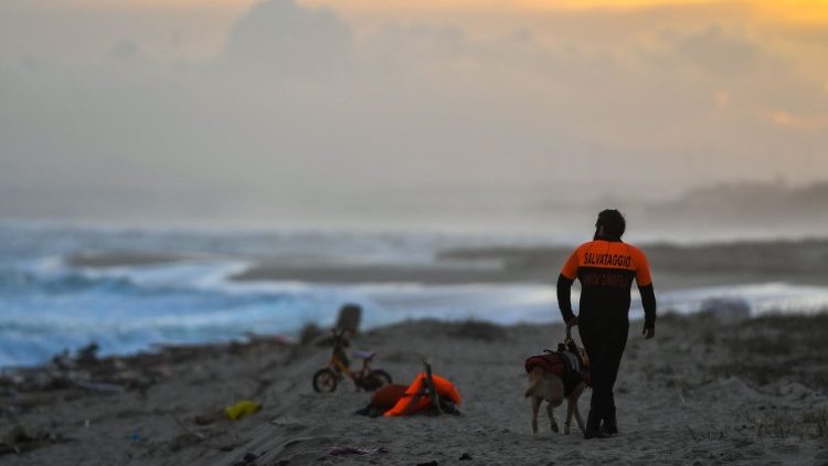 A member of the police and his dog patrol the beach where debris of the migrant boat shipwreck