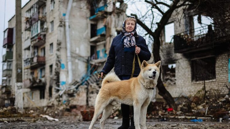 Tatiana Chvalun, 70, passeia com seu cachorro Buru por seu prédio residencial destruído em consequência do bombardeio de 9 de março passado, que matou 54 pessoas, na cidade de Izyum, região de Kharkiv, em 26 de fevereiro de 2023, em meio à invasão russa da Ucrânia. (Foto de Anatolii Stepanov / AFP)