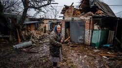 An elderly woman stands outside her destroyed house near Bakhmut