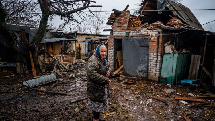 An elderly woman stands outside her destroyed house near Bakhmut