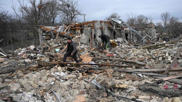 Pessoas vasculham os escombros de uma casa após um ataque russo na vila de Velyka Vilshanytsia, a cerca de 50 km de Lviv, em 9 de março de 2023. YURIY DYACHYSHYN / AFP