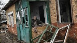 In Ukraine, an elderly woman stands in her home, which was damaged by shelling