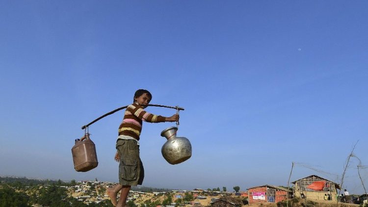 A Rohingya refugee collects water for daily consumption