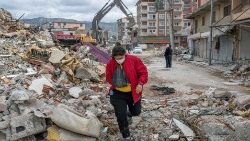 A woman walks on the rubble of a collapsed building in southeast Türkiye