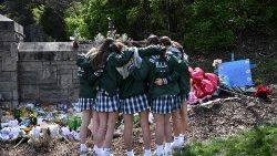 Girls embrace in front of a makeshift memorial for victims by the Covenant School