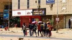 As pessoas já carregando seus pertences na capital Cartum neste domingo (16)