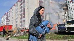 많은 건물을 파괴한 폭격이 있은 후 키이우에서 아기를 안고 피신하는 여성 