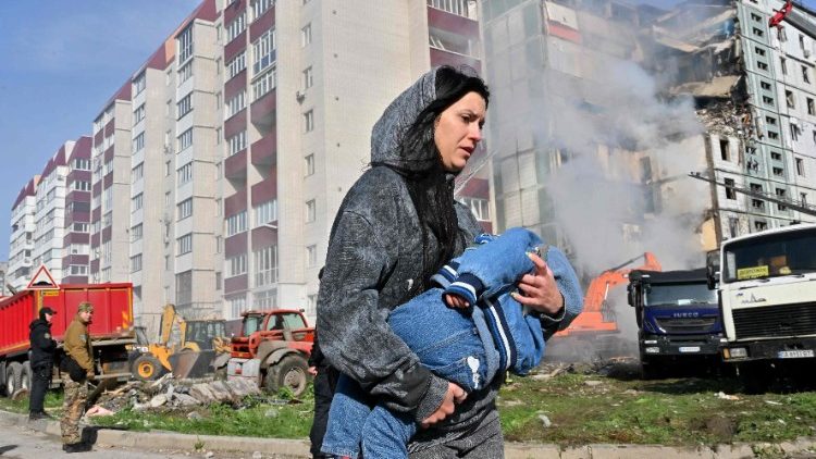 Una donna che scappa con il suo bambino a Kyiv dopo i bombardamenti che hanno danneggiato numerosi palazzi  (AFP or licensors)