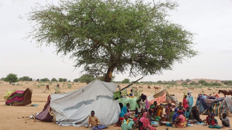 Sudanese refugees, most of them women and children, next to a makeshift shelter in the Chadian border village of Koufroun