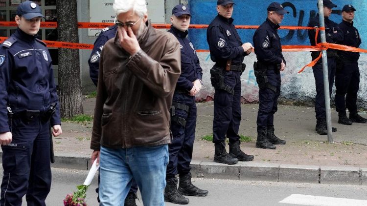 A man cries as he walks past police officers guarding the school entrance following a shooting at a school in the capital Belgrade on May 3, 2023