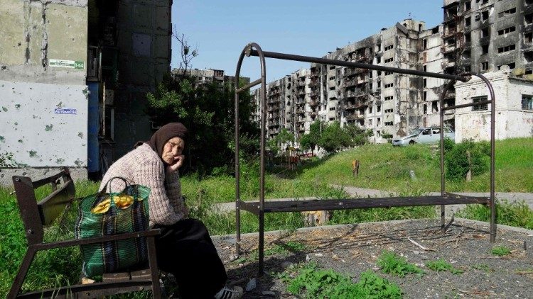 Kobieta przed zniszczonymi budynkami mieszkalnymi, Ukraina