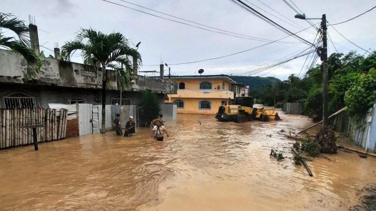 Varias personas vadean una calle inundada en Esmeraldas, Ecuador, el 4 de junio de 2023. Más de 500 personas fueron evacuadas el domingo.