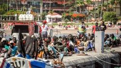 FILE PHOTO: Migrants rest on the pier after disembarking from a 'cayuco' (wooden boat) following a rescue operation on 4 July on the Spanish Canary island of Tenerife.