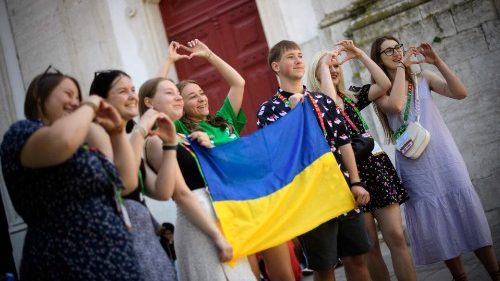 Peregrinos ucranianos posam com bandeira ucraniana após a Missa na Igreja da Graça, em Lisboa, no dia 3 de agosto (Foto de MIGUEL RIOPA/AFP)