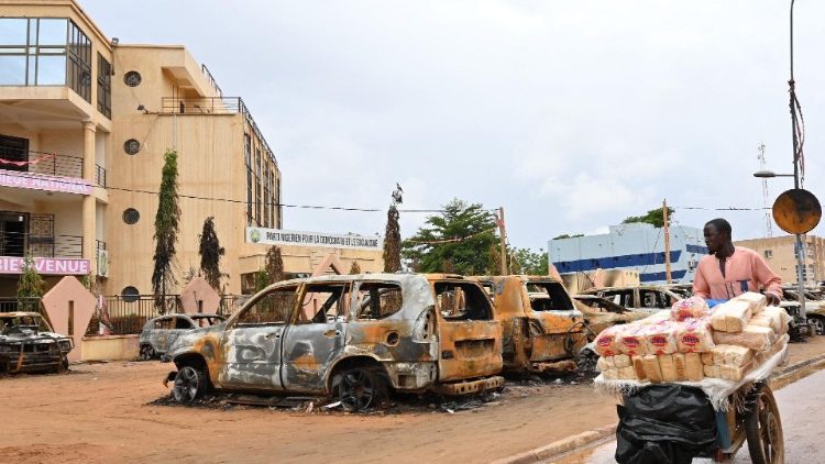 A street vendor pushes his cart past burned cars in Niamey's streets