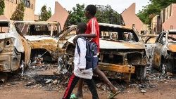Nigerien children walk past burned cars 