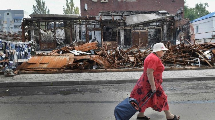 Uma mulher passa por um prédio em ruínas no centro de Donetsk em 12 de agosto de 2023, capital do autoproclamado estado da República Popular de Donetsk (DPR), no leste da Ucrânia. (Foto da AFP)