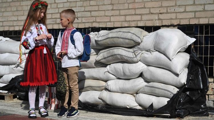 Estudantes ucranianos na frente de sacos de areia no pátio da escola após a cerimônia do Primeiro Sino, que marca o início do ano letivo na cidade de Lviv, no oeste da Ucrânia, em 1º de setembro de 2023. (Foto de YURIY DYACHYSHYN / AFP)