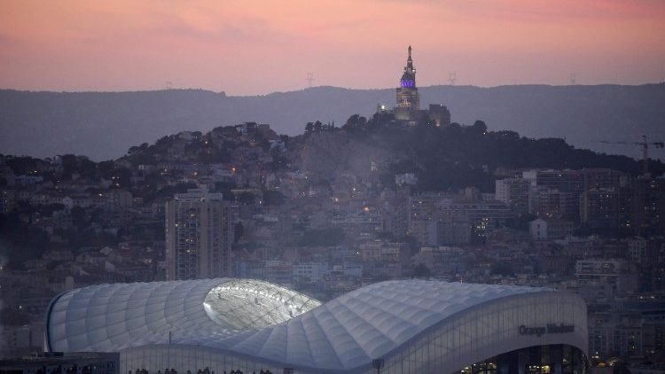 A imagem mostra o estádio, em primeiro plano, e a Basílica de 'Notre-Dame de la Garde' no alto