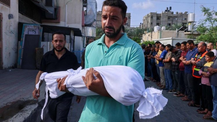 Palestinský muž nese  mrtvé tělo dítěte zabitého při izraelském nočním bombardování v pásmu Gazy.