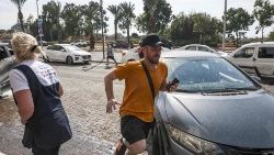 दक्षिणी इज्राएली शहर अश्कलोन में आग लगने की चेतावनी देने वाले सायरन सुनने के बाद छिपने के लिए भागते लोग