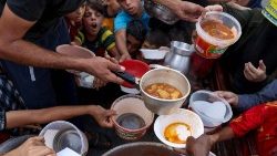Palestinian children receive food at a UN school in Rafah, southern Gaza
