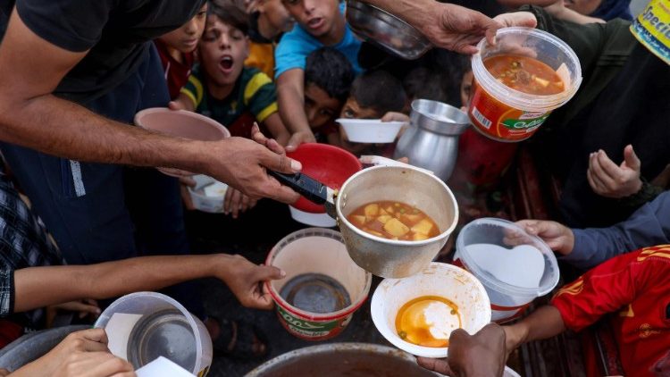Palestinian children receive food at a UN school in Rafah, southern Gaza
