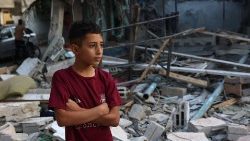 Chłopiec na tle ruin budynków zniszczonych przez bombardowania