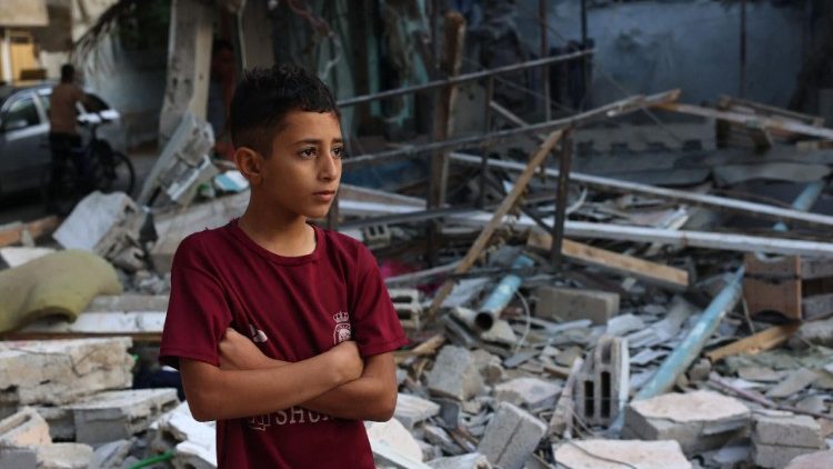 Chłopiec na tle ruin budynków zniszczonych przez bombardowania