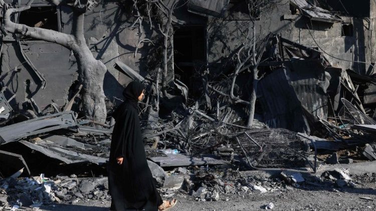 A Palestinian woman walks past the rubble of a destroyed building in Rafah