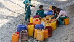 Children collect drinking water along a roadside in Jalalabad, Afghanistan