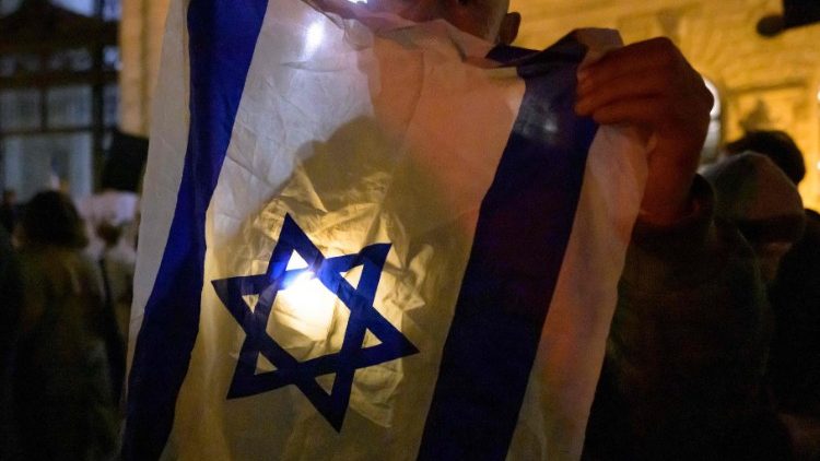 Ein Teilnehmer posiert mit einer israelischen Flagge und einem Licht während einer Aktion gegen Antisemitismus und das Vergessen des Holocausts (Wien, 2023)