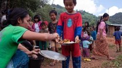 Esta foto tirada em 22 de outubro de 2023 mostra crianças recebendo comida em um abrigo temporário em um campo para deslocados internos (PDI) no município de Demoso, no estado de Kayah, em Mianmar.