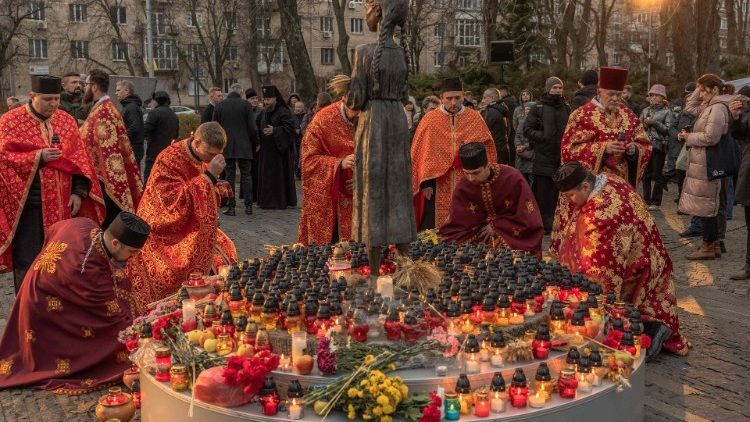 Sacerdotes ucranianos colocam velas na estátua da criança 'Memória Amarga da Infância', enquanto prestam homenagem às vítimas da fome de 1932-1933 no Museu Nacional do Holodomor-Genocídio em Kiev. (Photo by Roman PILIPEY / AFP)