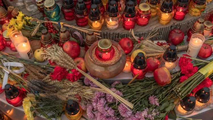 Esta fotografia tirada em 25 de novembro de 2023 mostra espigas de trigo, velas, maçãs e flores em frente à estátua infantil 'Memória Amarga da Infância', em homenagem às vítimas da fome de 1932-1933 no Museu Nacional do Holodomor -Genocídio em Kiev. (Photo by Roman PILIPEY / AFP)