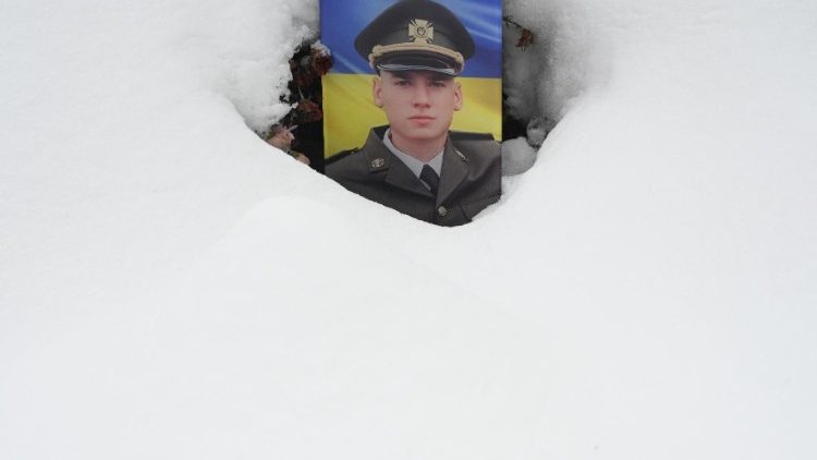 Retrato de um soldado ucraniano em seu túmulo, coberto de neve, durante o Dia das Forças Armadas da Ucrânia, no cemitério de Lychakiv, na cidade de Lviv. (Foto de YURIY DYACHYSHYN/AFP)
