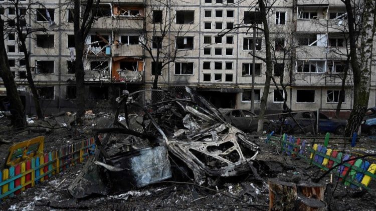 Esta fotografia tirada em 13 de dezembro de 2023 mostra um carro destruído próximo a um edifício residencial danificado após um ataque com mísseis em Kiev, em meio à invasão russa da Ucrânia. (Foto de SERGEI CHUZAVKOV/AFP)