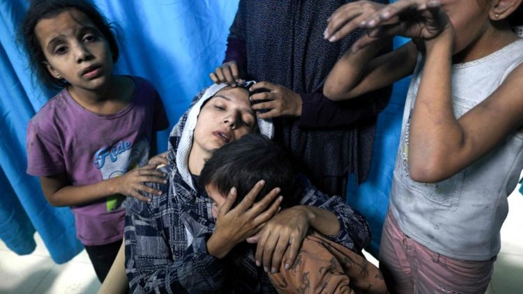 A wounded Palestinian woman is surrounded by her children upon arrival at Nasser Hospital in Khan Yunis in the southern Gaza Strip following Israeli air strikes