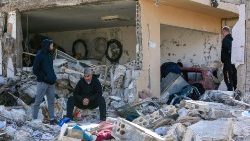 Des hommes examinent les décombres d'un bâtiment à Bint Jbeil, dans le sud du Liban, près de la frontière avec Israël, suite aux bombardements israéliens de la nuit précédente, le 27 décembre 2023,