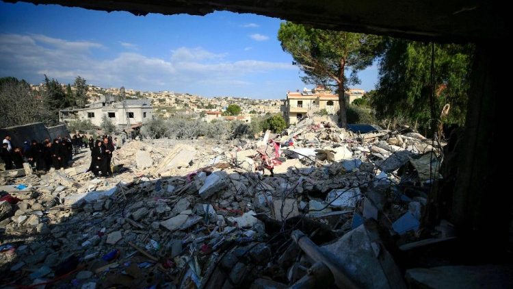 אנשים בודקים את הריסות הבניין בבינת ג'בייל בדרום לבנון ליד הגבול עם ישראל, לאחר הפצצה ישראלית בלילה הקודם ב-27 בדצמבר