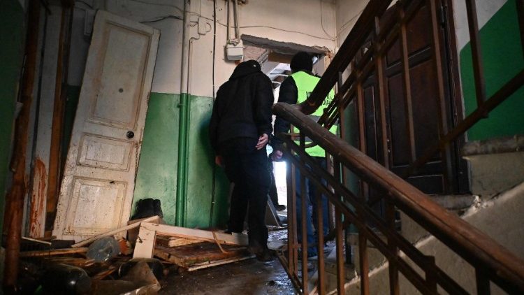 Policiais inspecionam um prédio de apartamentos destruído após o ataque noturno de drones russos em Kharkiv, 31 de dezembro de 2023. (Photo by SERGEY BOBOK / AFP)