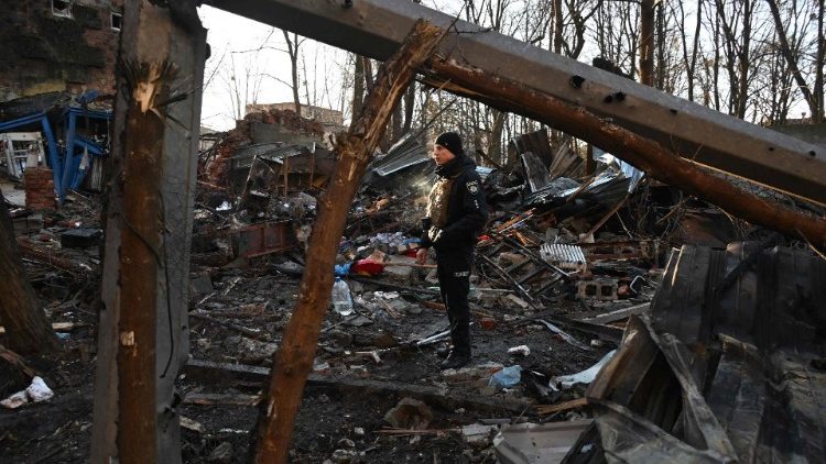 A policeman examines the damage outside an apartment building in Kharkiv