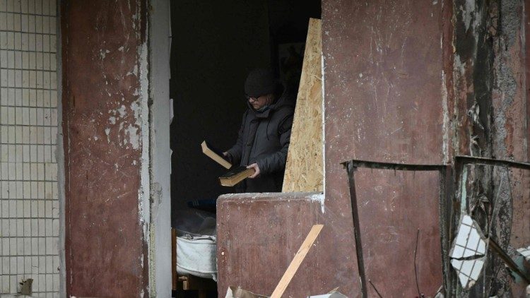 Um residente local inspeciona livros enquanto limpa os destroços de um apartamento em um prédio residencial fortemente danificado, três dias após um ataque com mísseis russos em Kiev.. (Photo by Genya SAVILOV / AFP)