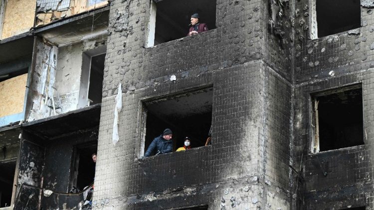 Moradores locais olham pelas janelas de um prédio residencial fortemente danificado, três dias após um ataque com mísseis russos em Kiev, em 5 de janeiro de 2024. (Photo by Genya SAVILOV / AFP)