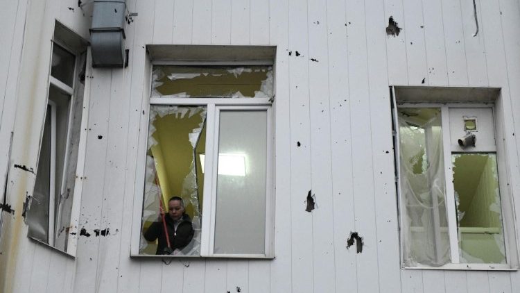 Uma mulher remove cacos de vidro de uma janela quebrada de um prédio hospitalar danificado como resultado de um bombardeio em Donetsk, na Ucrânia controlada pela Rússia, em 7 de janeiro de 2024, em meio ao conflito russo-ucraniano em curso. (Foto de STRINGER/AFP)