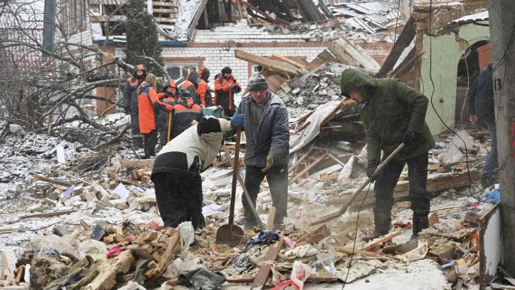 Equipes de resgate e residentes locais removem destroços após ataques russos, em Zmiiv, região de Kharkiv, em 8 de janeiro de 2024, em meio à invasão russa da Ucrânia. (Photo by SERGEY BOBOK / AFP)