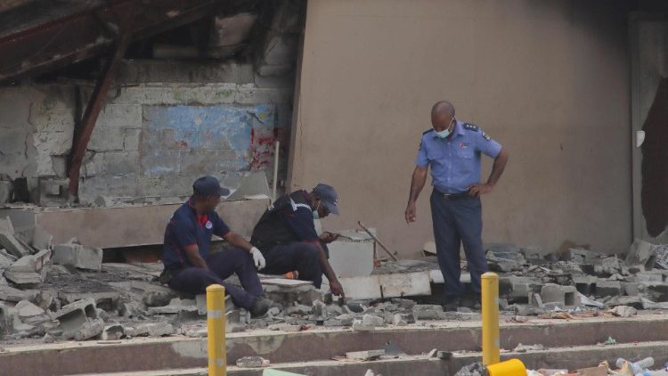A polícia trabalha no local de um edifício danificado em Port Moresby, em 12 de janeiro de 2023. Tropas patrulharam as ruas da capital de Papua Nova Guiné em 12 de janeiro, sob estado de emergência após tumultos que mataram 16 pessoas nas duas maiores cidades do país. (Foto da AFP)