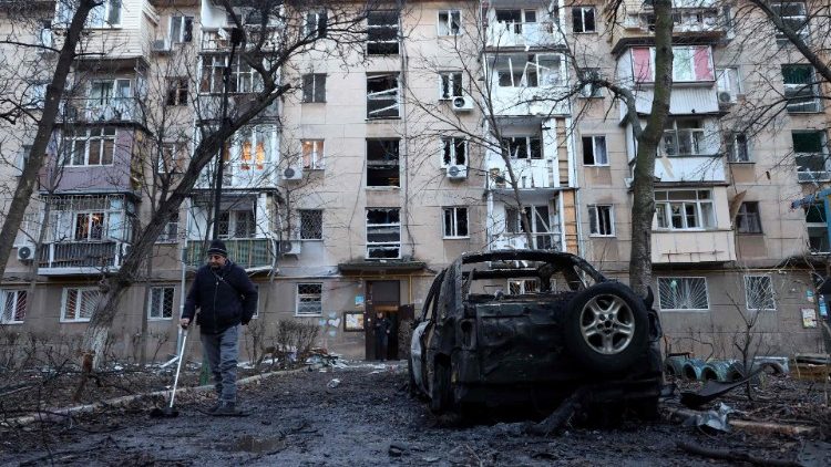 Um residente local passa por um carro destruído no pátio de um prédio residencial danificado após um ataque de drone em Odessa em 17 de janeiro de 2024. (Foto de Oleksandr GIMANOV/AFP)