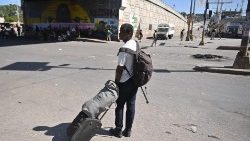 Ein Mann steht mit seinem Koffer auf der Straße in der Hauptstadt Porte-au-Prince, während landesweit Proteste gegen die Regierung laufen (Bild vom 18. Januar 2024)