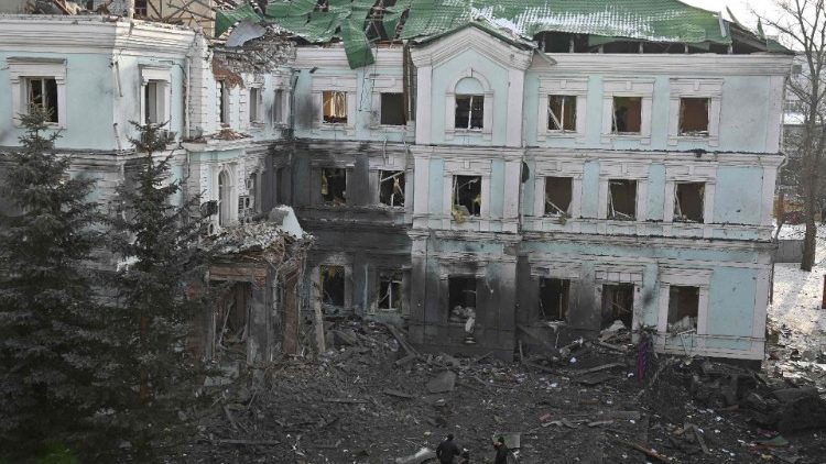 Moradores locais conversam do lado de fora de um prédio fortemente danificado em Kharkiv, em 24 de janeiro de 2024, um dia após maciço ataque russo com mísseis.. (Foto de SERGEY BOBOK/AFP)